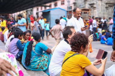 THIRUVANNAMALAI, INDIA - 24 Aralık 2019: Hindu hacılar ve yabancı turistler tapınak merdivenlerinde oturuyor ve dinleniyorlar