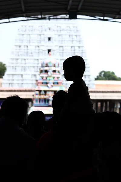 Een kind zit op en knuffelt zijn vader in de achtergrond van een hindoe tempel. — Stockfoto