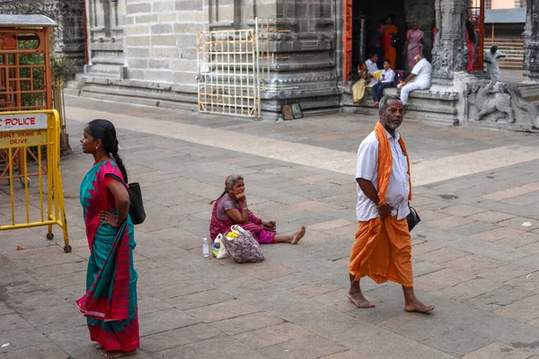 THIRUVANNAMALAI, INDIA - December 24, 2019: idős nő ül egy templom előtt, Egy csoport ember ül a bejárat közelében a hindu templom — Stock Fotó