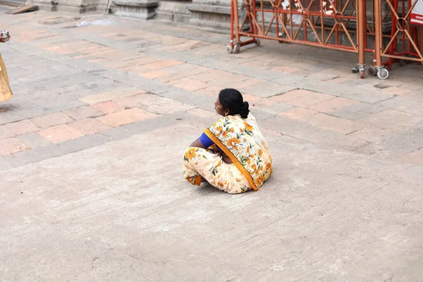 THIRUVANNAMALAI, INDIA - 2019. december 24.: Indiai nő ül egy templom előtt, emberek ülnek a hindu templom bejáratánál — Stock Fotó