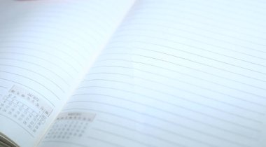 Beyaz arkaplanda satırları olan boş sayfalarla açılan günlük, seçici odaklı yakın çekim.