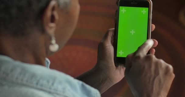 Attractive elderly black woman swiping her finger on a green screen mobile phone — Stock Video