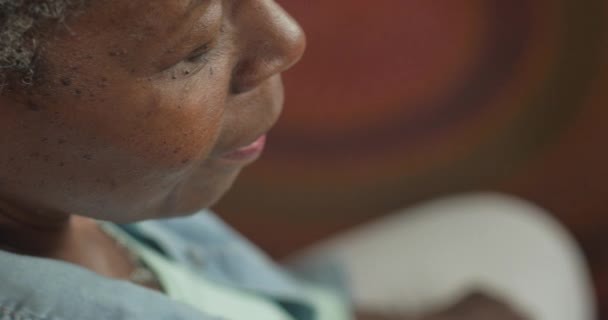 Concerned elderly black woman hears something and looks towards the camera — Stock Video