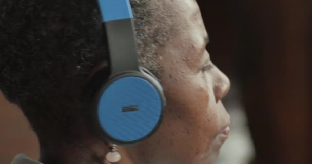 Youthful black senior woman listening to music with headphones — Stock Video