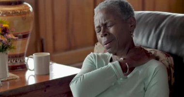 Yaşlı siyah kadın acı içinde buz torbası onun omzuna koyar.