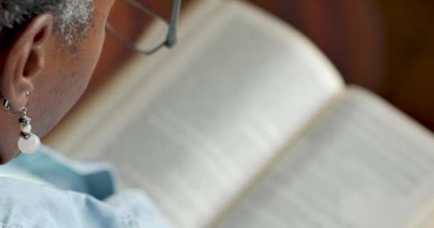 Femme noire âgée met ses lunettes de lecture tout en regardant un livre — Video