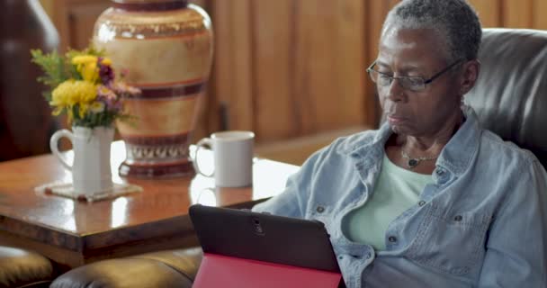 Atrakcyjne starsze czarna kobieta przy użyciu cyfrowego tabletu w jej salonie - dolly — Wideo stockowe