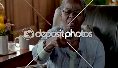 Hayal kırıklığına uğramış kızgın yaşlı siyah kadın bir tv uzaktan kumanda kullanmaya çalışıyor