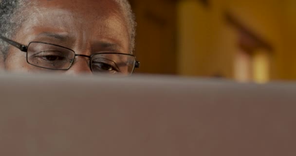 Dolly tiro de uma pessoa idosa negra olhando para um monitor de computador — Vídeo de Stock