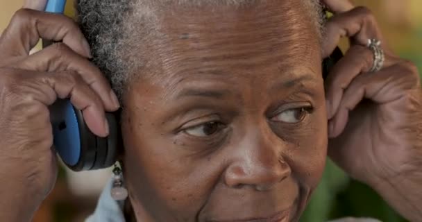 Чернокожая пожилая женщина надевает наушники и наслаждается музыкой — стоковое видео