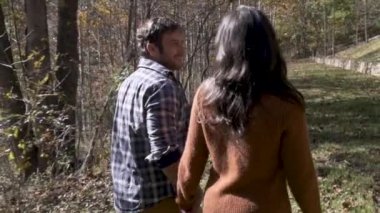 Ağaçlarla dolu bir parkta yürürken bir kadına yol açan bir adamın profili