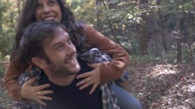 Mutlu adam arkasında eğlenceli olmak güzel bir gülümseyen kadın taşıyan dışarıda