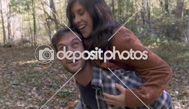 Ormanda yürüyüş yaparken onun arkasına çekici bir kadın taşıyan gülümseyen adam