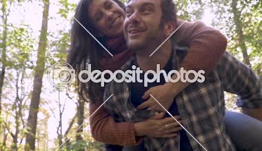 Ormanda arka açık havada Genç bir kadın taşıyan mutlu sağlıklı adam