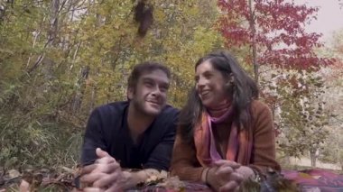 Sonbahar sırasında bir battaniye üzerinde yatarken bir öpüşme çifti düşen yaprakları