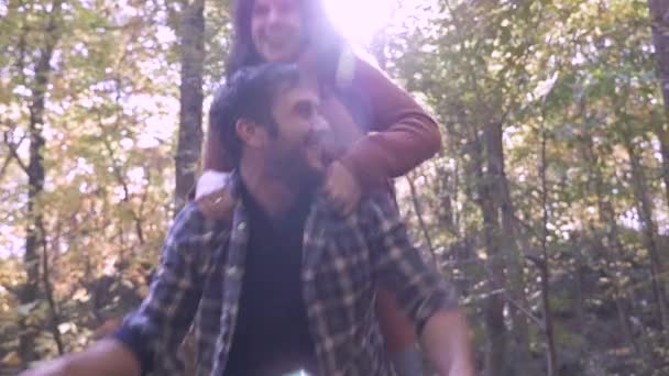 Hermosa pareja enamorada jugando al cerdito en el bosque con el resplandor del sol — Vídeos de Stock