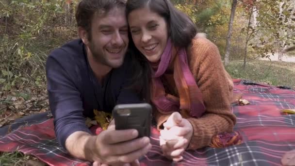 Boston Terrier deita-se ao lado de um casal tirando uma selfie com seu telefone inteligente — Vídeo de Stock