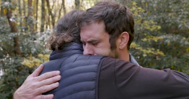 Dwóch młodych mężczyzn przytulanie się na zewnątrz w parku konsultując się nawzajem w ciągu dnia — Wideo stockowe