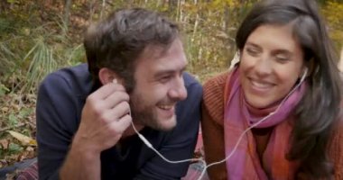 İyi görünümlü çift birlikte aynı kulaklıklar paylaşımı müzik dinlerken