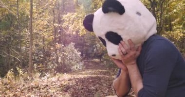 Üzgün Panda bir parkta veya ormanda ağlıyor ve gözyaşlarını silerek dışarıda oturuyor