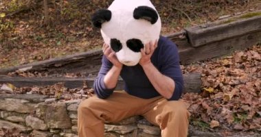 Bir panda kafa maskesi giyen adam üzgün ve ağlıyor