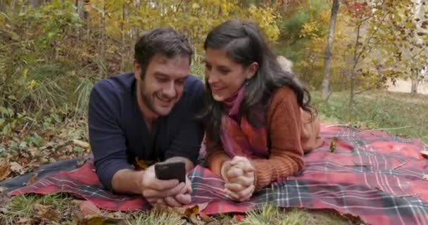 Retrato sonriente de una atractiva pareja joven usando un teléfono móvil juntos — Vídeo de stock