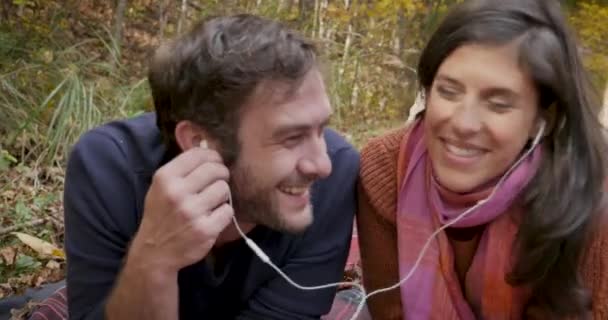 Pareja guapa escuchando música juntos compartiendo los mismos auriculares — Vídeo de stock