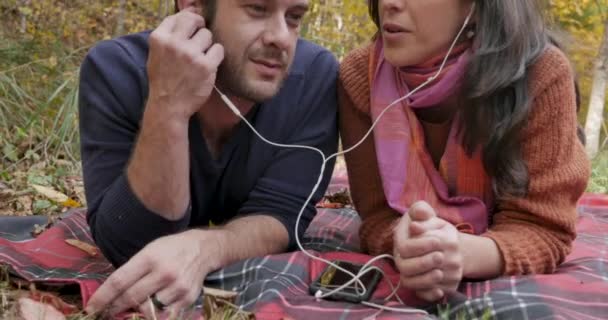 Grúa de una pareja escuchando la misma música juntos fuera — Vídeo de stock