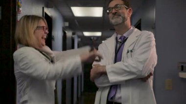 Kadın doktor kafasını sallayarak bir erkek doktor yanında kollarını feragat