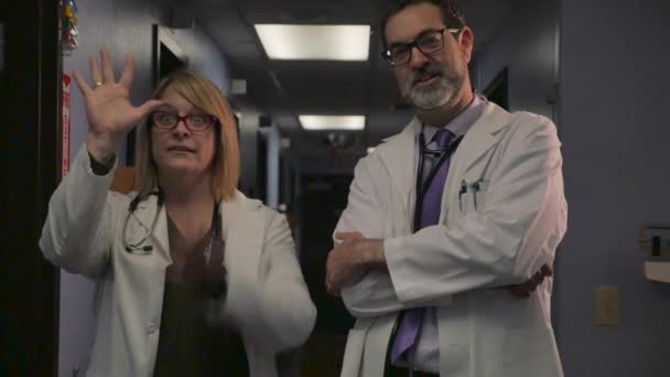 Жінка-лікар діє як мим поруч з роздратованим лікарем-чоловіком — стокове відео