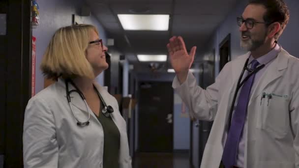 Deux docteurs en haut cinq, serrent la main, et regardent directement la caméra — Video