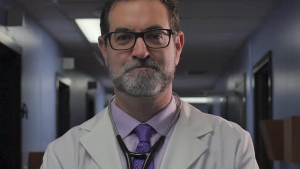Портрет красивого мужчины-врача, улыбающегося и смотрящего в камеру в клинике — стоковое видео