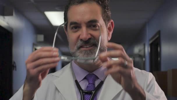 Portrait of a male doctor putting on eyeglasses, smiling, and looking at camera — Stock Video
