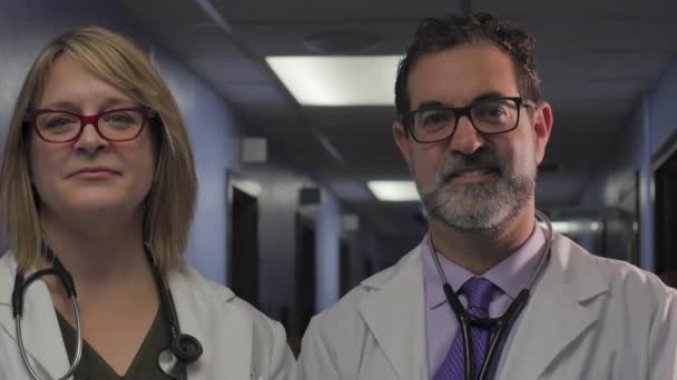 Портреты двух врачей, улыбающихся в больничном коридоре - выстрел в куклу — стоковое видео