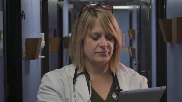 Profissional médico feminino rolando em um tablet digital em um corredor do hospital — Vídeo de Stock