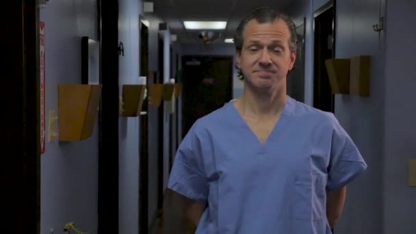 Άνθρωπος γιατρός ή νοσοκόμα φορώντας μπλε τρίβει στέκεται σε ένα διάδρομο νοσοκομείο — Αρχείο Βίντεο