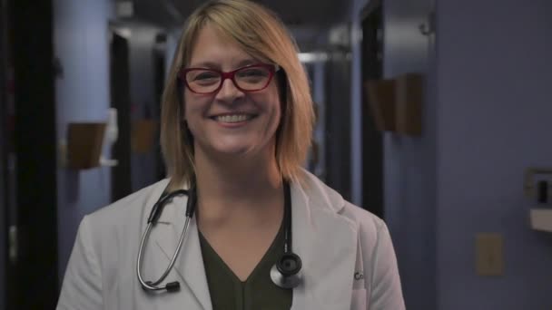 Привлекательная женщина-врач скрещивает руки и улыбается в камеру — стоковое видео