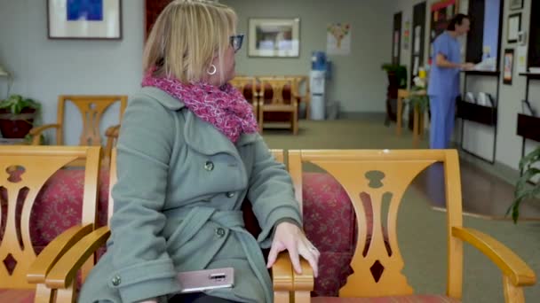 Frustrated woman patient sitting in a hospital or medical office waiting room — Stock Video