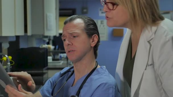Γυναίκες και άνδρες γιατροί που δείχνουν ένα ψηφιακό δισκίο σε μια ιατρική εγκατάσταση — Αρχείο Βίντεο