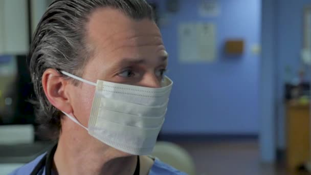 Male doctor or nurse with a face mask turning to look at the camera — Stock Video