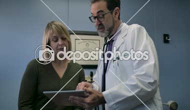 Bayan hasta ile dijital tablette bilgi paylaşan mutlu erkek doktor