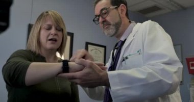 Bir SmartWatch tıbbi uygulamasını kullanmak için nasıl bir kadın hasta gösteren erkek doktor