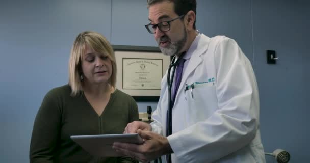 Happy male doctor sharing information on a digital tablet with a female patient — Stock Video