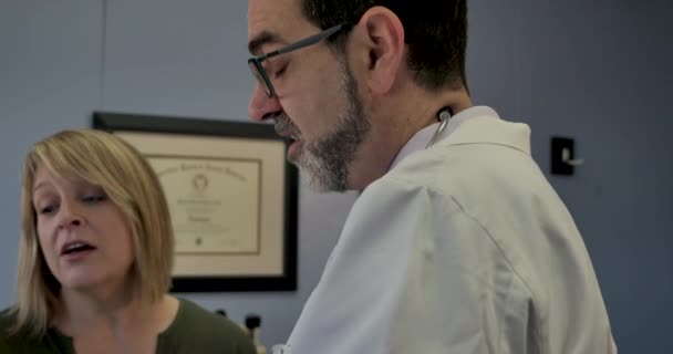 Male doctor reviewing medical history or information with a female patient — Stock Video