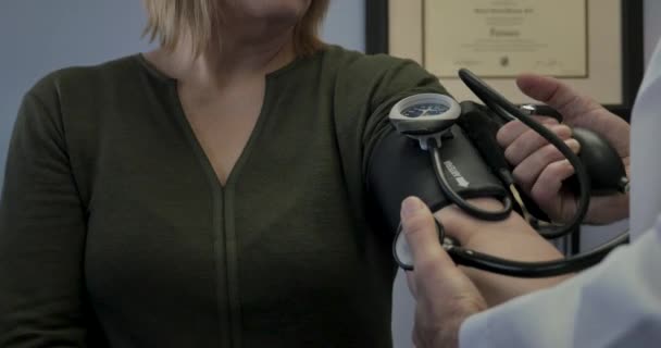 Doctor or nurse checking blood pressure on a female patient — Stock Video