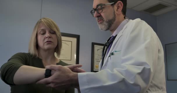 Mężczyzna lekarz nauczania kobiet pacjenta jak korzystać z inteligentnego zegarka zdrowia aplikacji — Wideo stockowe