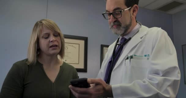 Paciente do sexo feminino aprendendo com um médico do sexo masculino como usar um aplicativo de telefone inteligente médico — Vídeo de Stock