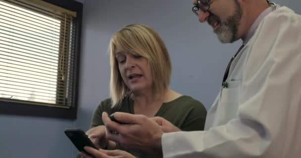 Paciente femenina sincronizando datos médicos desde su teléfono a un teléfono médico — Vídeo de stock