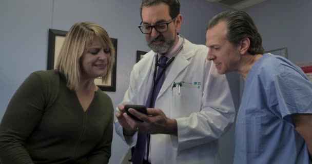 Врач делится информацией о смартфоне с медсестрой и пациентом — стоковое видео