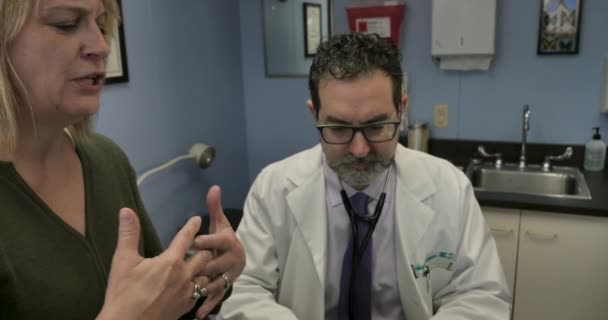 Медсестра або хірург перериває пацієнта, який розмовляє зі своїм лікарем-чоловіком — стокове відео